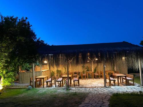 a patio with wooden tables and chairs at night at Limonlu Bahçe Butik Otel in Karaburun