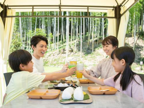 a family sitting at a table eating food at BAMBOO RESORT MIHAMA　繋 in Mihama
