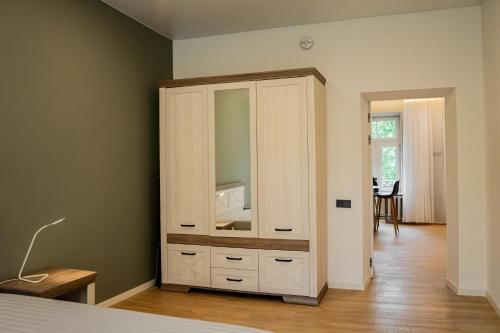 ein Schlafzimmer mit einem weißen Schrank mit Spiegel in der Unterkunft Meridiano apartamentai in Klaipėda