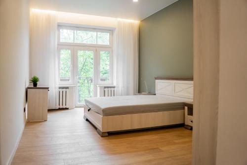 ein Schlafzimmer mit einem Bett und einem großen Fenster in der Unterkunft Meridiano apartamentai in Klaipėda