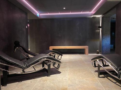 a salon with black chairs and a purple lighting at Hôtel 16 | 150 Montagne & Spa Nuxe in Vars
