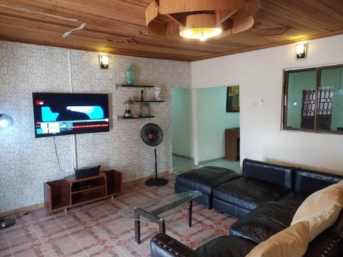 a living room with a couch and a flat screen tv at Charming 2-Bed Cottage in Benin City in Benin City