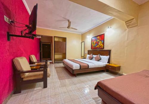 Hotel Sai leela - Shirdi في شيردي: غرفه فندقيه بسرير وكرسي
