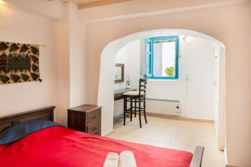 a bedroom with a red bed and a desk at Karai traditional house in Astypalaia Town
