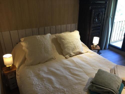 a bed with white sheets and pillows and two lamps at Lou Aubrac Hébergement aux portes de l'Aubrac 