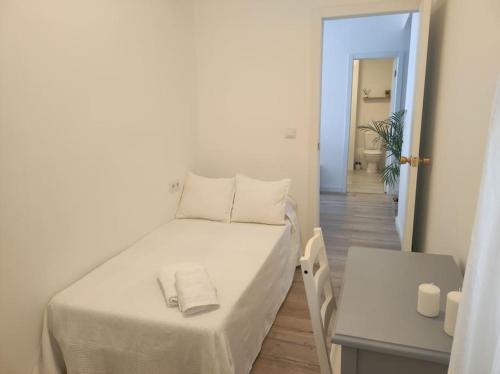 Un pequeño dormitorio con una cama blanca y una mesa en Casa Dina II., en O Carballiño
