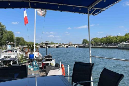 łódź na rzece z krzesłami i stołem w obiekcie Péniche de charme au pont Alexandre III w Paryżu