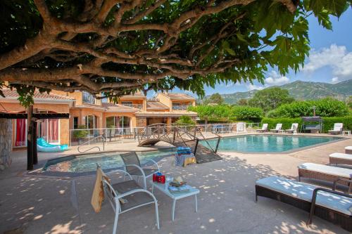 - une piscine avec des chaises et une table en face d'un bâtiment dans l'établissement U Guadellu - Piscine Chauffée, à Oletta