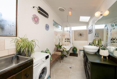 a bathroom with a sink and a washing machine at Delphi, Adelaide Hills Garden BnB in Mylor