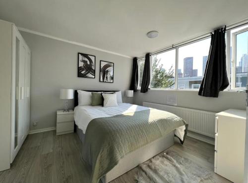 ein weißes Schlafzimmer mit einem Bett und zwei Fenstern in der Unterkunft Lovely 4bed property, London 8min to Oxford Street in London