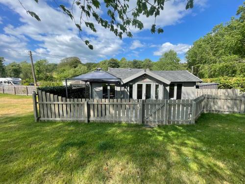a fence in front of a house with a gazebo at Daisy Cabin in Kincardine OʼNeil