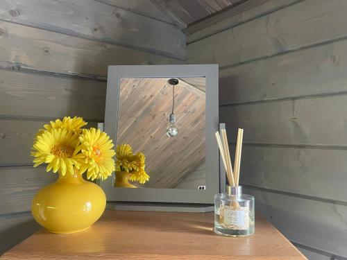 a yellow vase sitting on a table with yellow flowers at Daisy Cabin in Kincardine OʼNeil