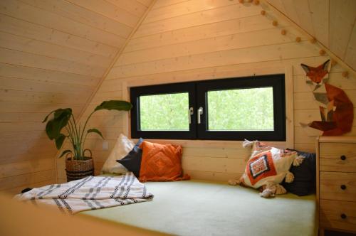 um quarto com uma cama numa casa com uma janela em Lisia Górka - domek nad jez. Krosino - Głęboczek, poj Drawskie em Głęboczek