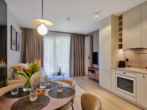韋巴的住宿－Apartament Natura D33 Porto Łeba，厨房以及带桌椅的起居室。