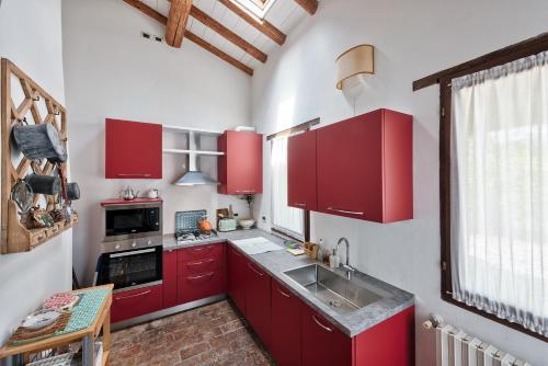 a kitchen with red cabinets and a sink at Country house Viaro_150sqm in Vanzo