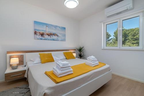 a white bedroom with a large bed with yellow pillows at Beachfront Apartment with parking in Slatine