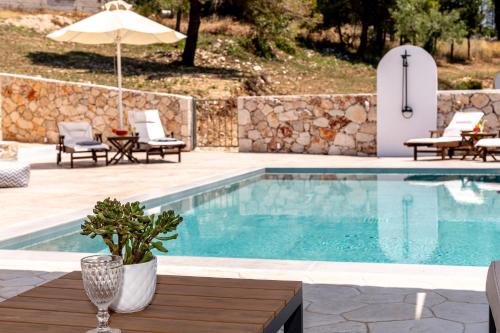 a pool with a table and chairs and an umbrella at Misovounous Natural Park Villa by "elite" in Agios Leon