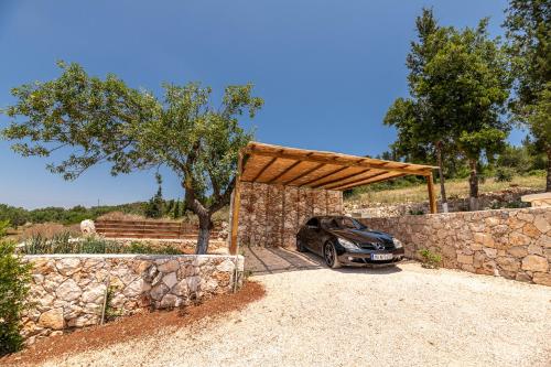 a car parked in front of a stone wall at Misovounous Natural Park Villa by "elite" in Agios Leon
