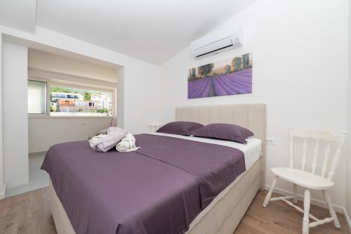 sypialnia z łóżkiem z fioletową pościelą i krzesłem w obiekcie Apartmani Tona w Baskiej Vodzie