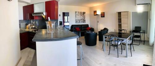 une cuisine et un salon avec une table et des chaises dans l'établissement Le Rouge et Le Noir 45 m2 sur Coursives Gde Terrasse Port Nature Naturiste, au Cap d'Agde