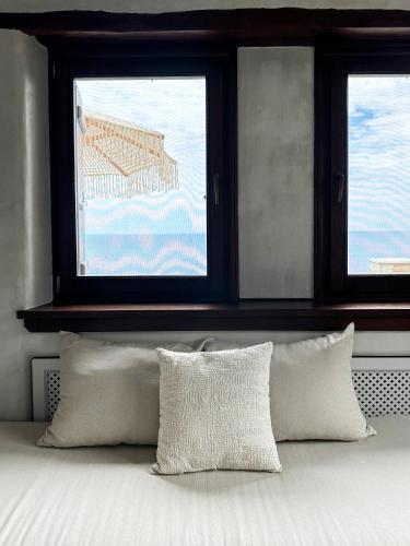 a bedroom with two windows and a bed with pillows at Agapitos Villas & Guesthouses in Agios Ioannis Pelio