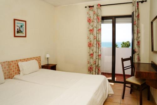 a bedroom with a bed and a desk and a window at Cheerfulway Ouravista Apartamentos in Albufeira
