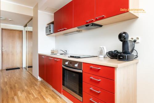 a red kitchen with red cabinets and a stove at Daily Apartments - Viru Keskus in Tallinn