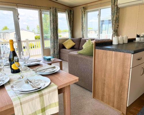 eine Küche und ein Wohnzimmer mit einem Tisch und einem Sofa in der Unterkunft Haven Holiday Home at Kent Coast Allhallows in Rochester