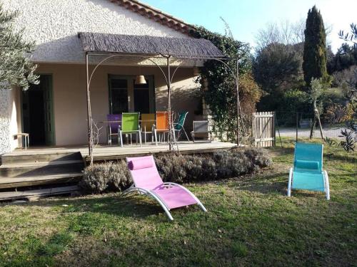 duas cadeiras sentadas na relva em frente a uma casa em Villa au milieu des vignes em Vacqueyras