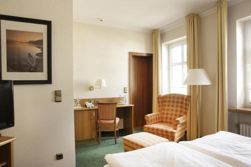 a hotel room with a bed and a chair and a desk at Hotel Kirchspiels Gasthaus in Nortorf