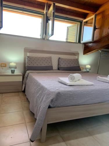 um quarto com uma cama grande e 2 janelas em LE CASTELLA BEACH S.F.2 em Le Castella