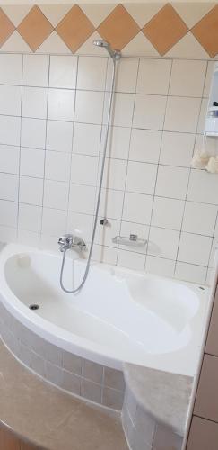 a white bath tub with a shower in a bathroom at sunset house in Vitalades
