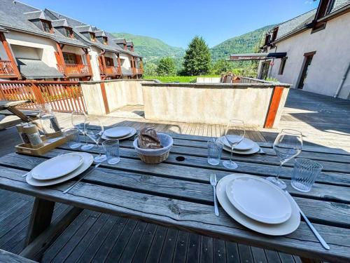 een houten tafel met borden en wijnglazen erop bij La suite d'Aure, linge en option in Vignec
