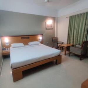 a bedroom with a bed and a couch and a chair at Kottaram Hotels Ottaplam in Palakkad