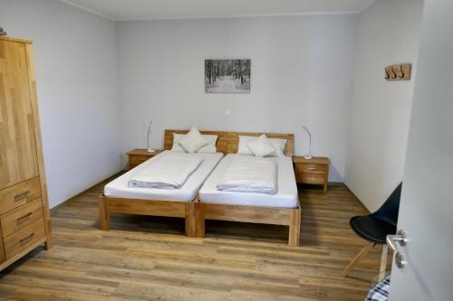 una camera da letto con letto, lenzuola bianche e pavimenti in legno di Ferienwohnungen Büffel a Heimbach