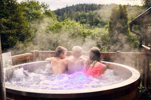 un grupo de tres personas en una bañera de hidromasaje en Horská chata 3 SKALKY so saunou a jacuzzi kaďou en Smižany