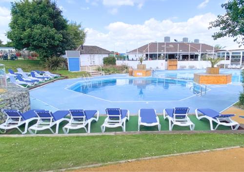 a large pool with blue chairs in the grass at Haven Holiday Home at Kent Coast Allhallows in Allhallows