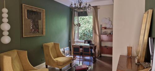 a living room with green walls and chairs and a desk at Hotel Valerì in Rome