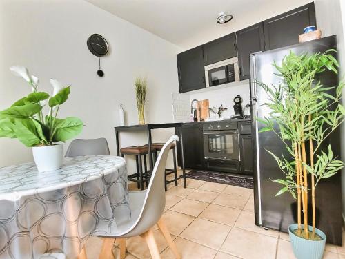 a kitchen with black cabinets and a table with plants at Le 3plex - Coeur de Vertou - Original in Vertou
