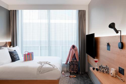 a hotel room with a bed and a large window at Moxy Manchester City in Manchester