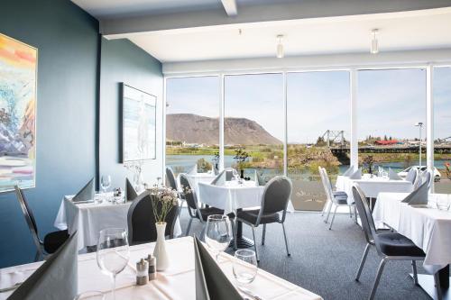 a restaurant with white tables and chairs and large windows at Hotel Selfoss in Selfoss