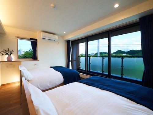 a hotel room with two beds and a large window at Rakuten STAY HOUSE Kujukuri Ichinomiya 103 3LDK with BBQ terrace in Ichinomiya