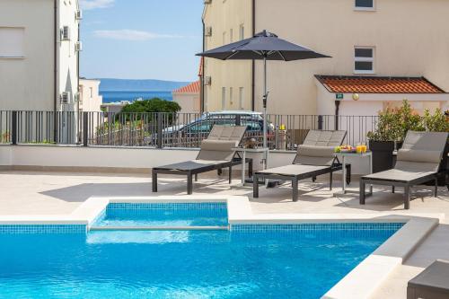 A&D Deluxe apartments Dani with swimming pool في بروماجنا: مسبح مع كراسي ومظلة على مبنى