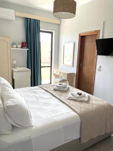 a bedroom with a large white bed with towels on it at wave rooms sea view in Chania