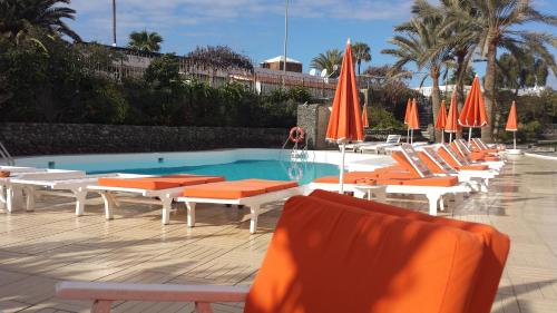 eine Reihe von Stühlen und Sonnenschirmen neben einem Swimmingpool in der Unterkunft Apartamento Paco in Playa del Ingles