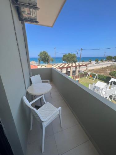 balcón con mesa, sillas y vistas al océano en wave rooms sea view, en La Canea