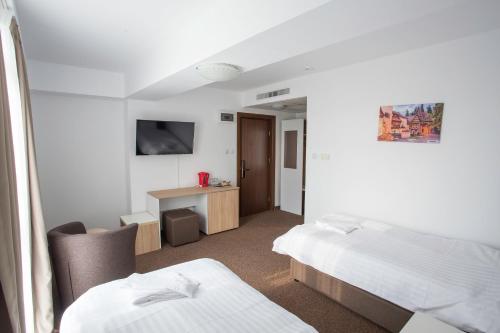 Habitación de hotel con 2 camas y escritorio en Acomodoro Residence, en Bucarest