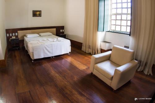 a bedroom with a bed and a chair at Pousada Convento do Carmo in Cachoeira