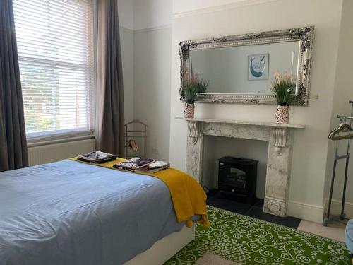 Schlafzimmer mit einem Bett, einem Kamin und einem Spiegel in der Unterkunft Elegant Spacious Apartment in Heart of St Leonards in Hastings