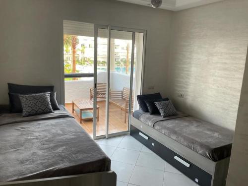 1 dormitorio con 2 camas y balcón en Appartement pieds dans l’eau à sidi Rahal, en Sidi Rahal